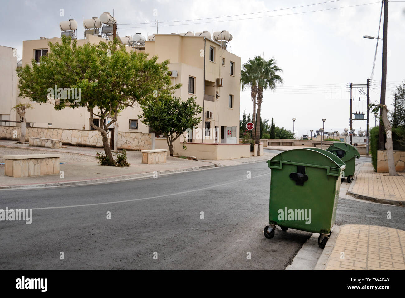 Clean tidy city street of the European city. Garbage containers are green in the yard. Stock Photo