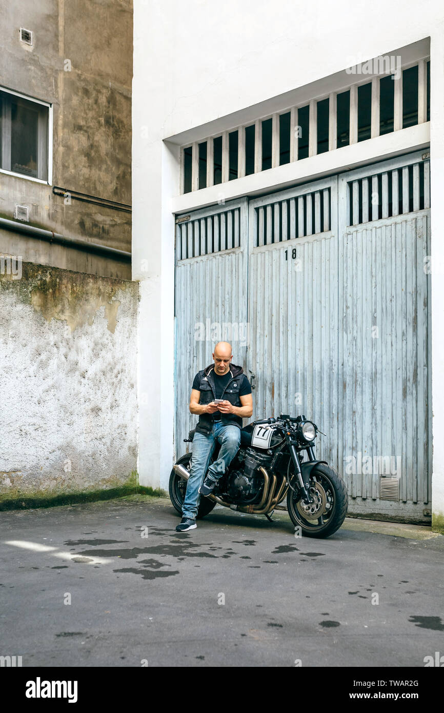 Biker looking mobile sitting on motorcycle Stock Photo