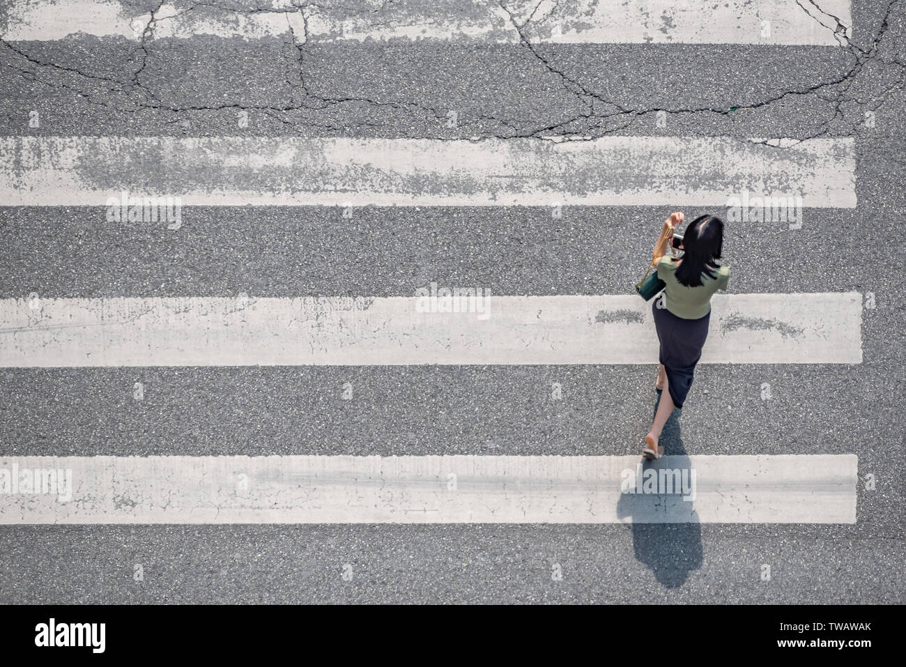 Chengdu, Sichuan province, China - June 12, 2019 : Young chinese woman walking on a zebra crossing aerial top view on a sunny day Stock Photo