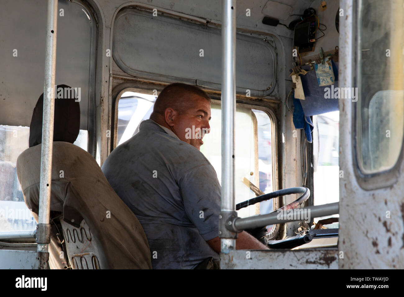 A Cuban bus driver, driving a rundown old empty bus in Trinidad, Cuba. Stock Photo