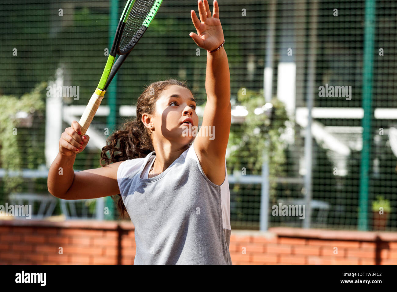 Girl teenager with long curly hair with a racket in his hands. Girl ...