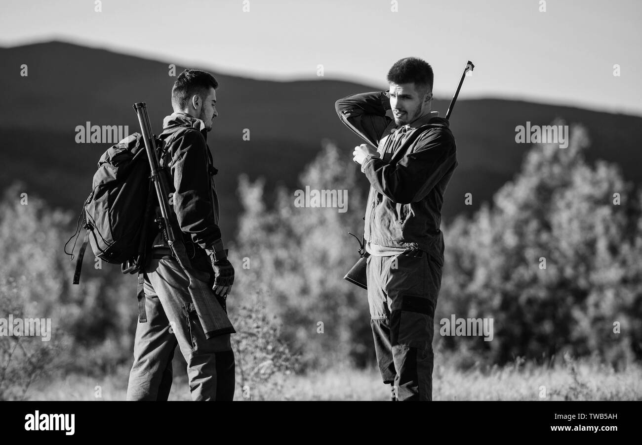 Friendship of men hunters. Military uniform. Army forces. Camouflage. Hunting skills and weapon equipment. How turn hunting into hobby. Man hunters with rifle gun. Boot camp. charging hunting rifle. Stock Photo