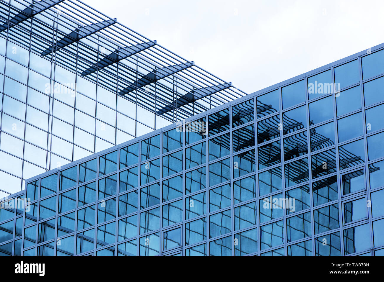 Business building with modern glass exterior on blue sky background with reflection. Stock Photo