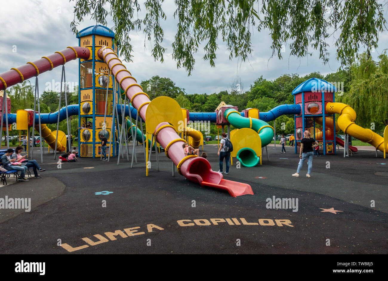Parents and children relaxing at the slides in a playground areas of Parcul Lumea Copiilor, the Children's World Park in central Bucharest, Romania. Stock Photo