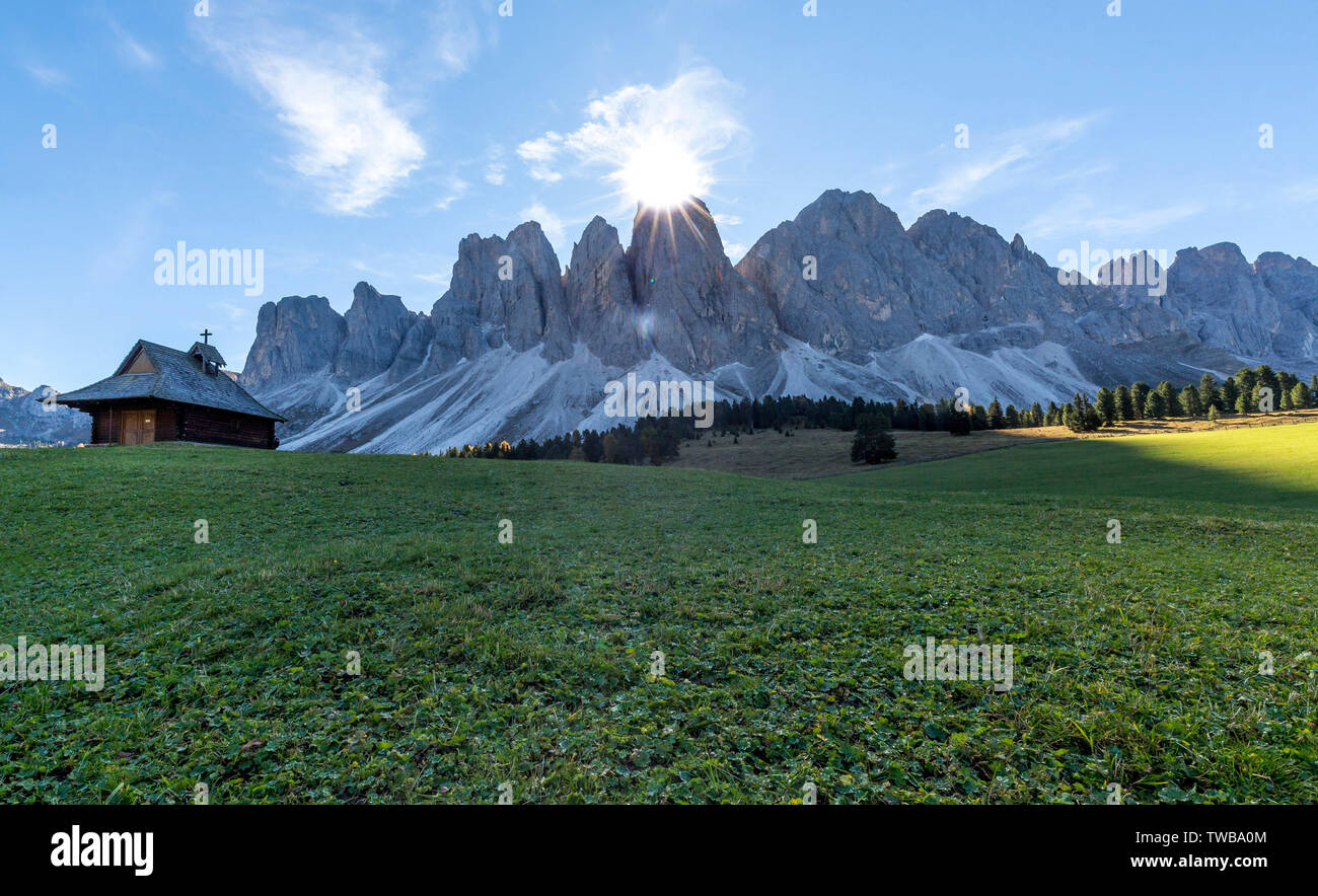 Sunburst over the Odle peaks and chapel at Glatschalm, Puez Odle, Dolomites, Funes, Bolzano province, South Tyrol, Italy Stock Photo