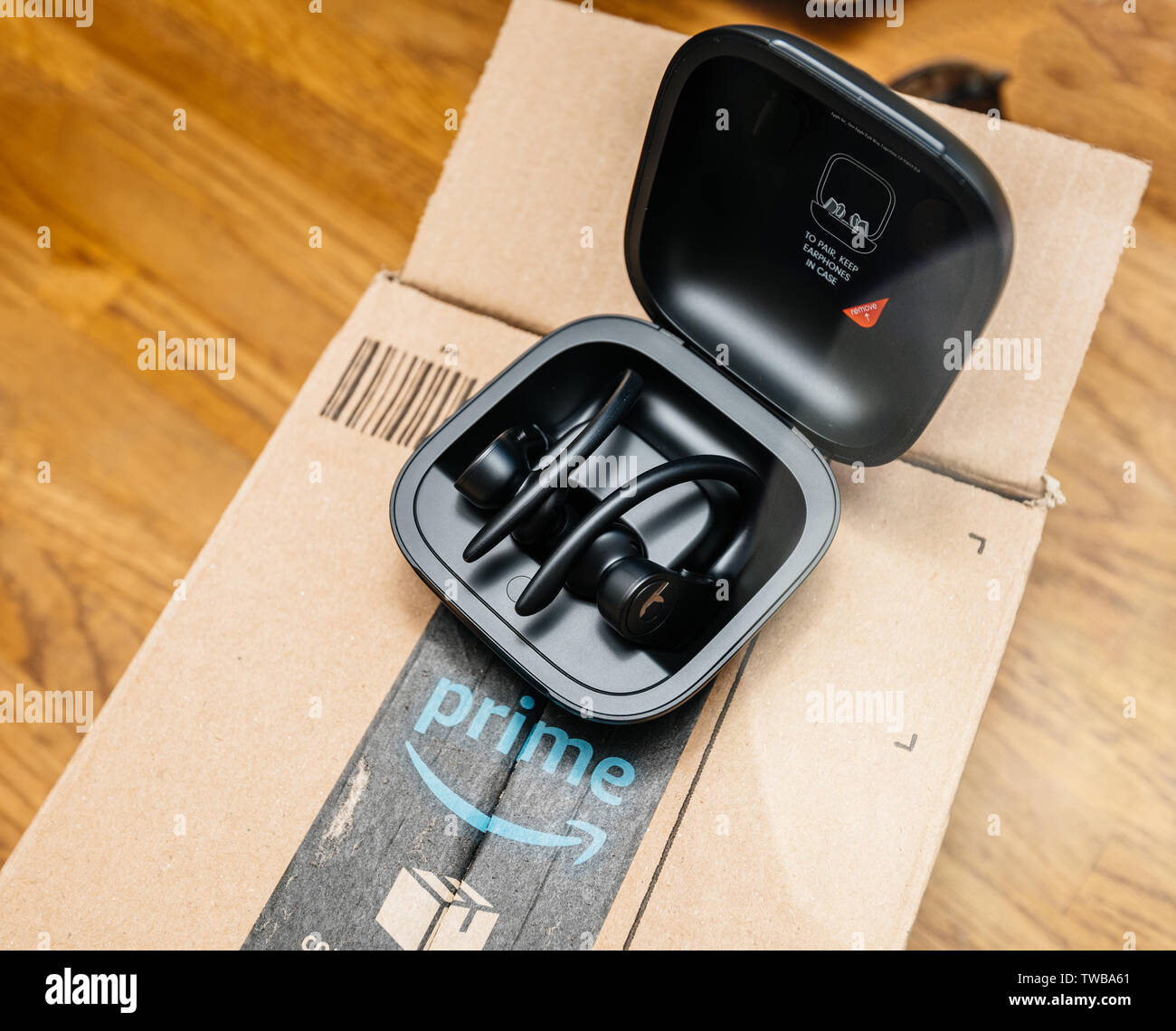 Paris, France - Jun 17, 2019: wooden table with Amazon Prime cardboard parcel and Powerbeats Pro Beats by Dr Dre wireless high-performance earphones waterproof and workout professional headphones Stock Photo