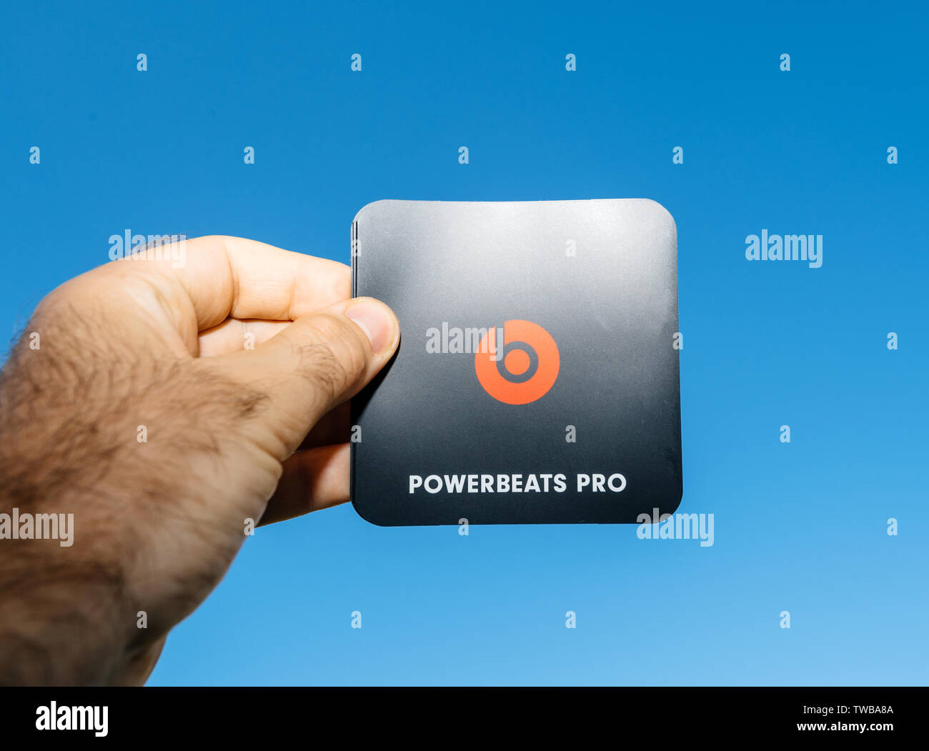 Paris, France - Jun 17, 2019: Man hand holding red black sticker with logotype insignia brand during Powerbeats Pro Beats by Dr Dre - blue clear sky in the background Stock Photo