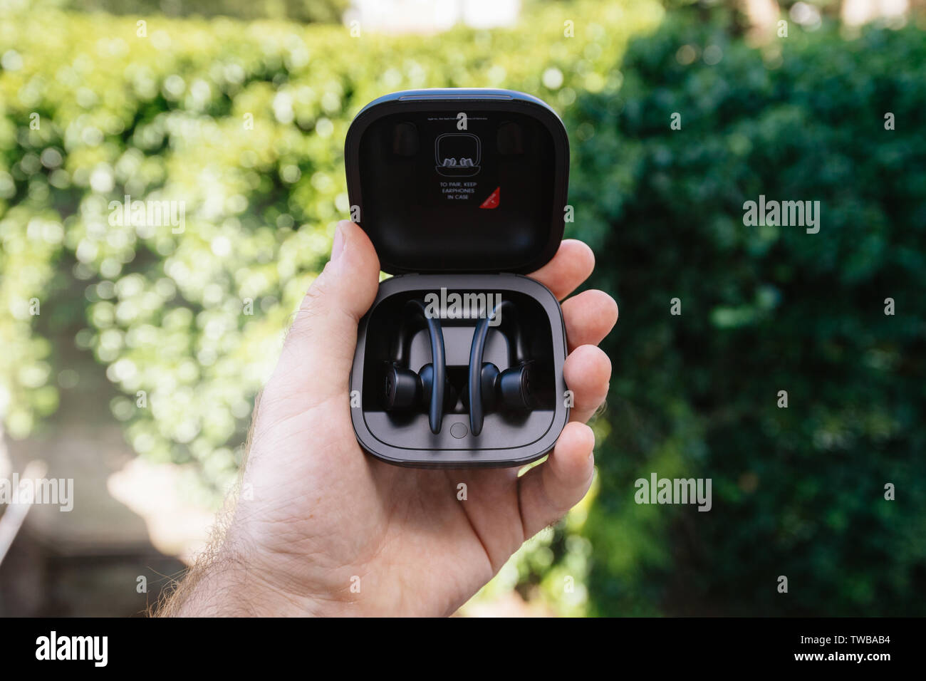 Paris, France - Jun 17, 2019: Powerbeats Pro Beats by Dr Dre wireless high-performance earphones charging case after unboxing man hand holding admiring the new music device Stock Photo