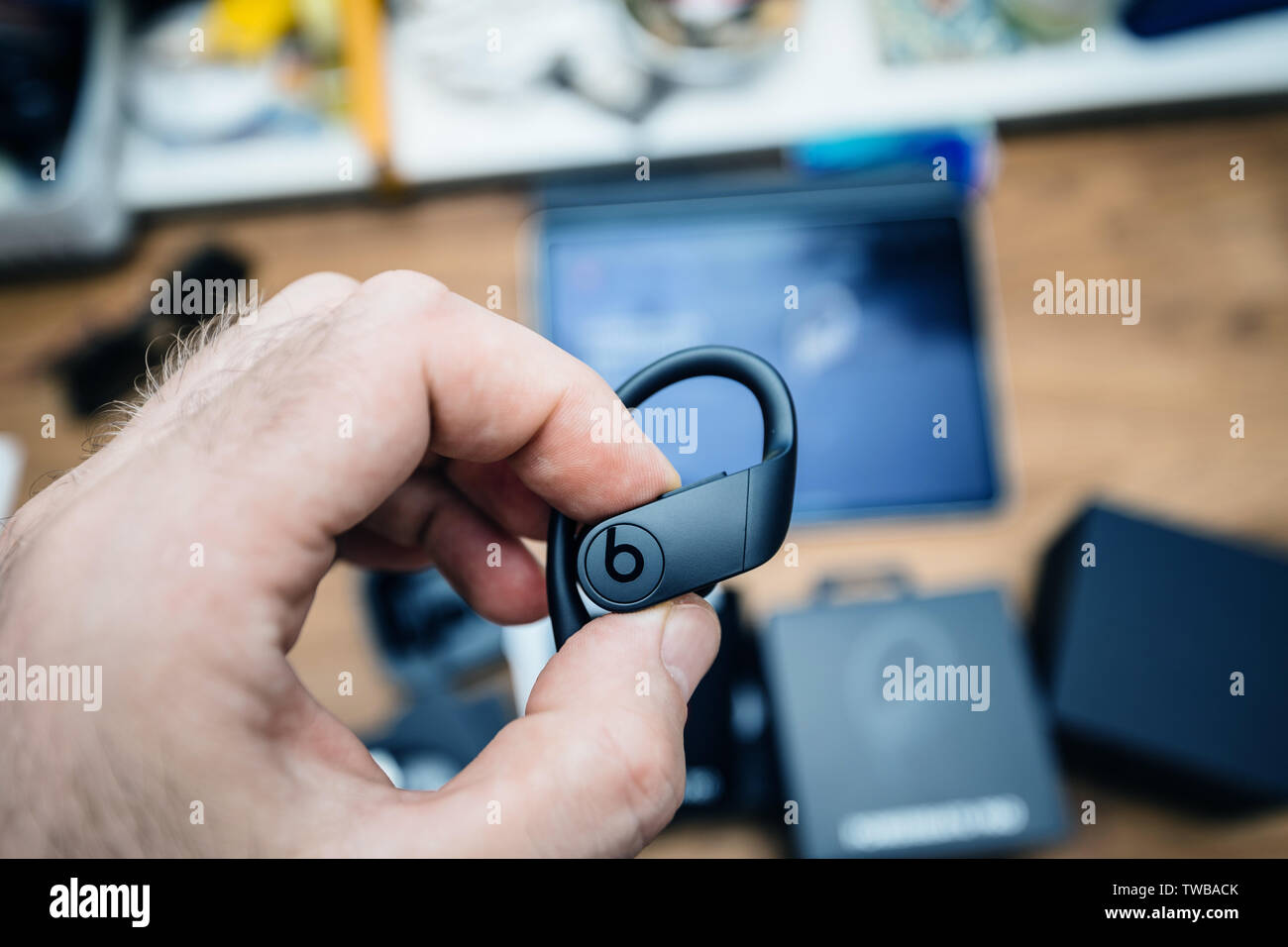 Paris, France - Jun 17, 2019: Man hand holding Powerbeats Pro Beats by Dr Dre wireless high-performance earphones waterproof and workout professional headphones during unboxing Stock Photo