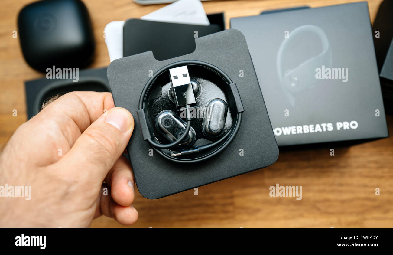 Paris, France - Jun 17, 2019: Man hand holding Eartips with four size options, Lightning to USB-A charging cable for apple Powerbeats Pro Beats by Dr Dre wireless headphones during unboxing Stock Photo