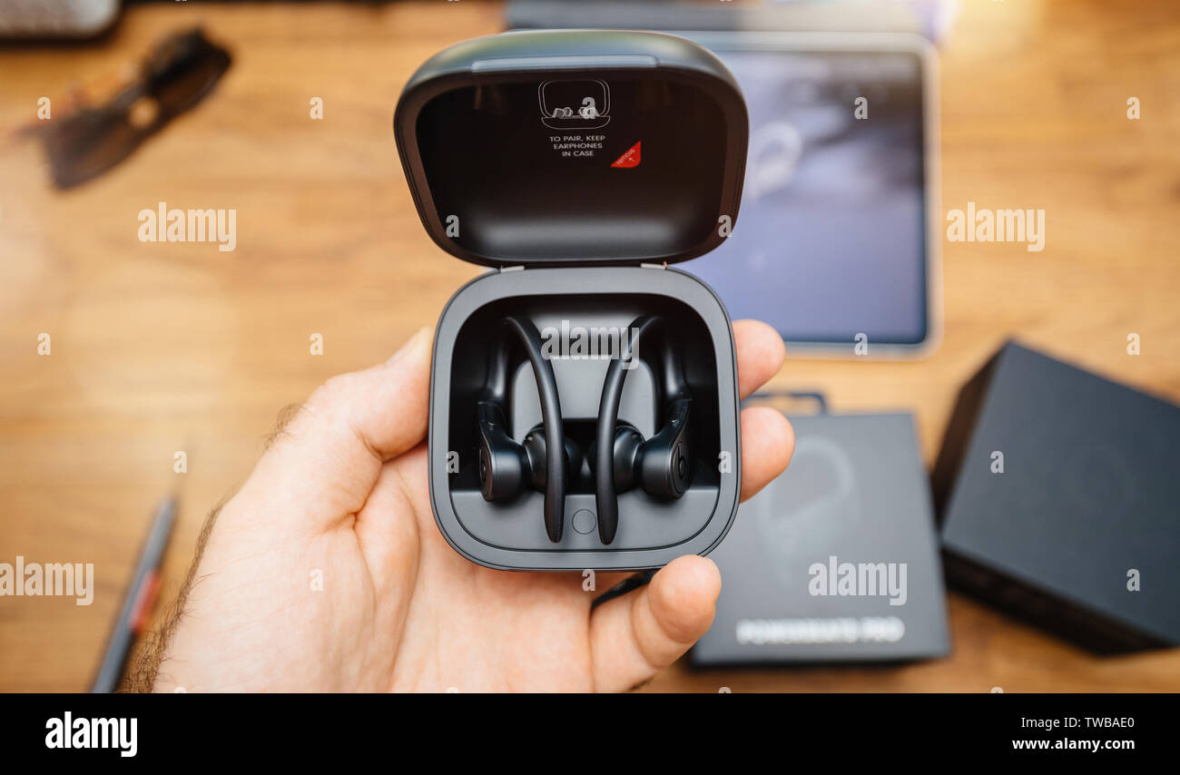 Paris, France - Jun 17, 2019: Man hand holding Powerbeats Pro Beats by Dr Dre wireless high-performance earphones waterproof and workout professional headphones in their charging case - view from above Stock Photo