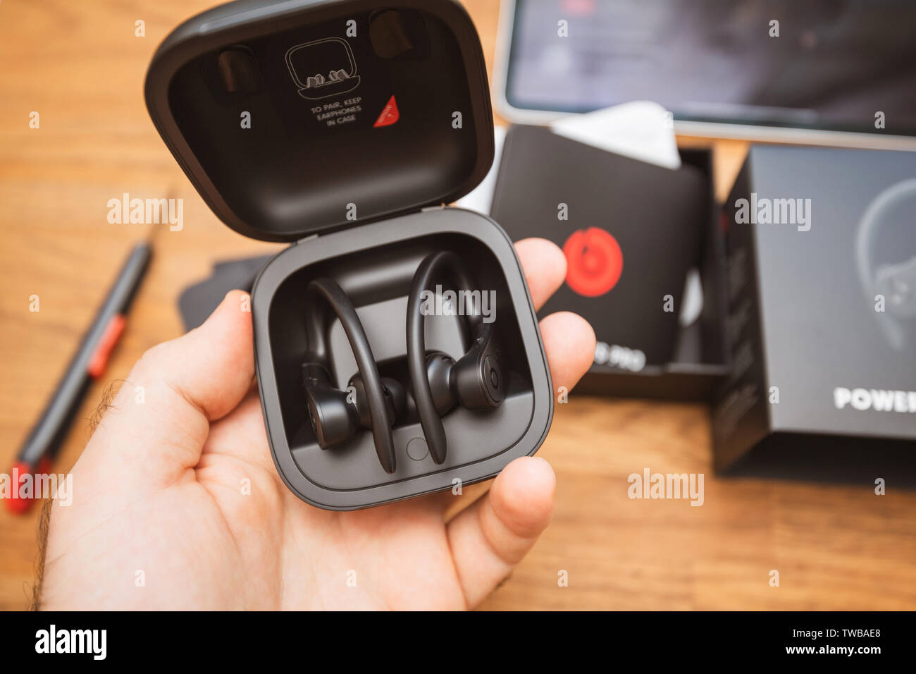 Paris, France - Jun 17, 2019: Man hand admiring the Powerbeats Pro Beats by Dr Dre wireless high-performance earphones waterproof and workout professional headphones in their charging case - unboxing Stock Photo