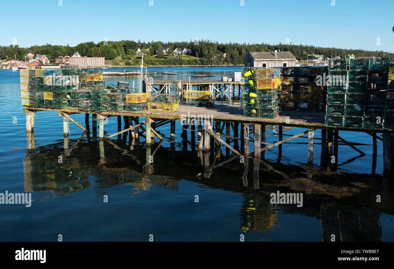 A dock over the blue water of Bass Harbor Maine, has many lobster traps