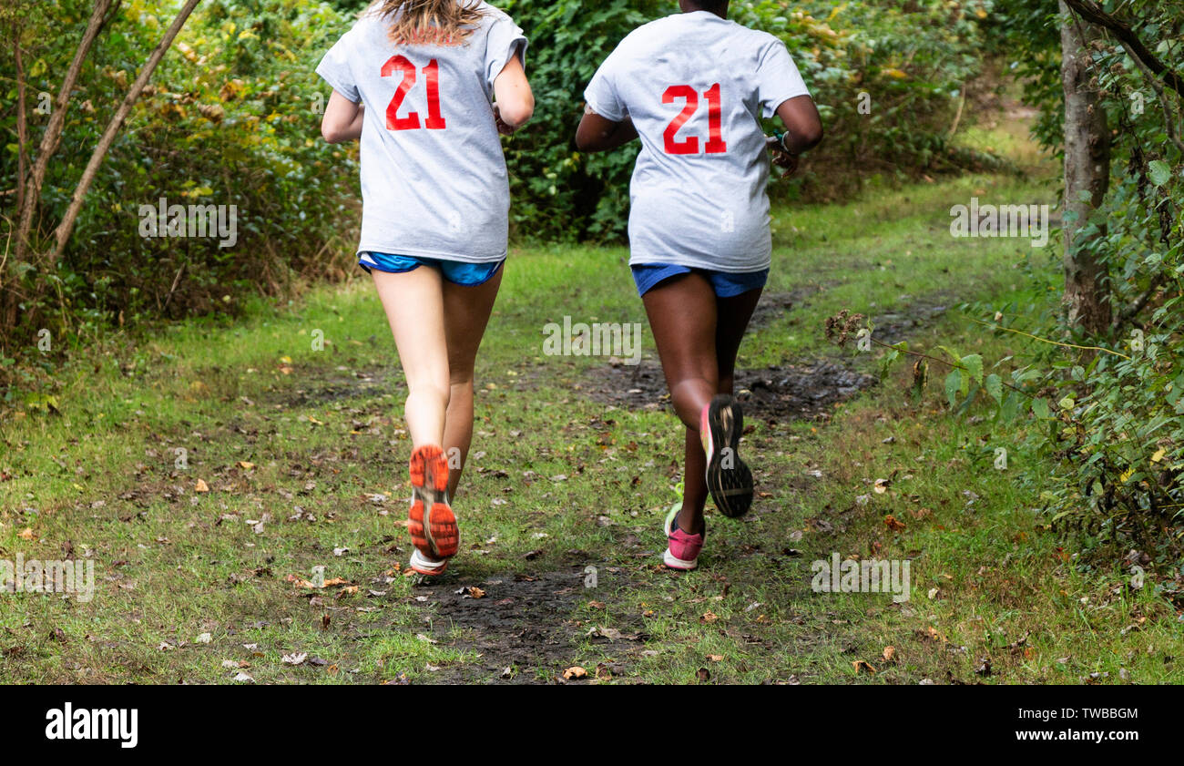 Two high school cross country runners are running side by side on a