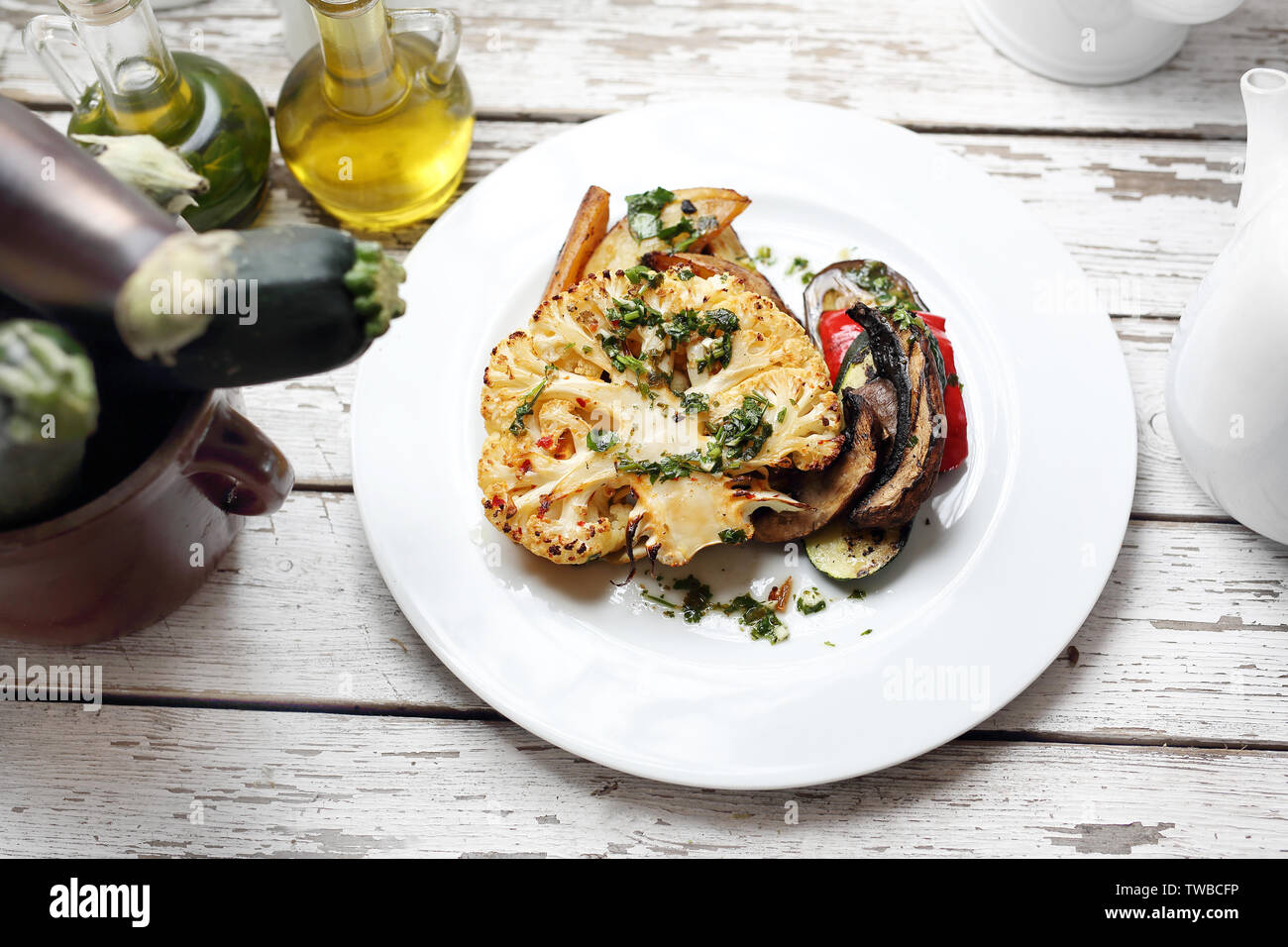 Vegetarian dish.  Baked cauliflower with mushrooms served with herbs. Stock Photo