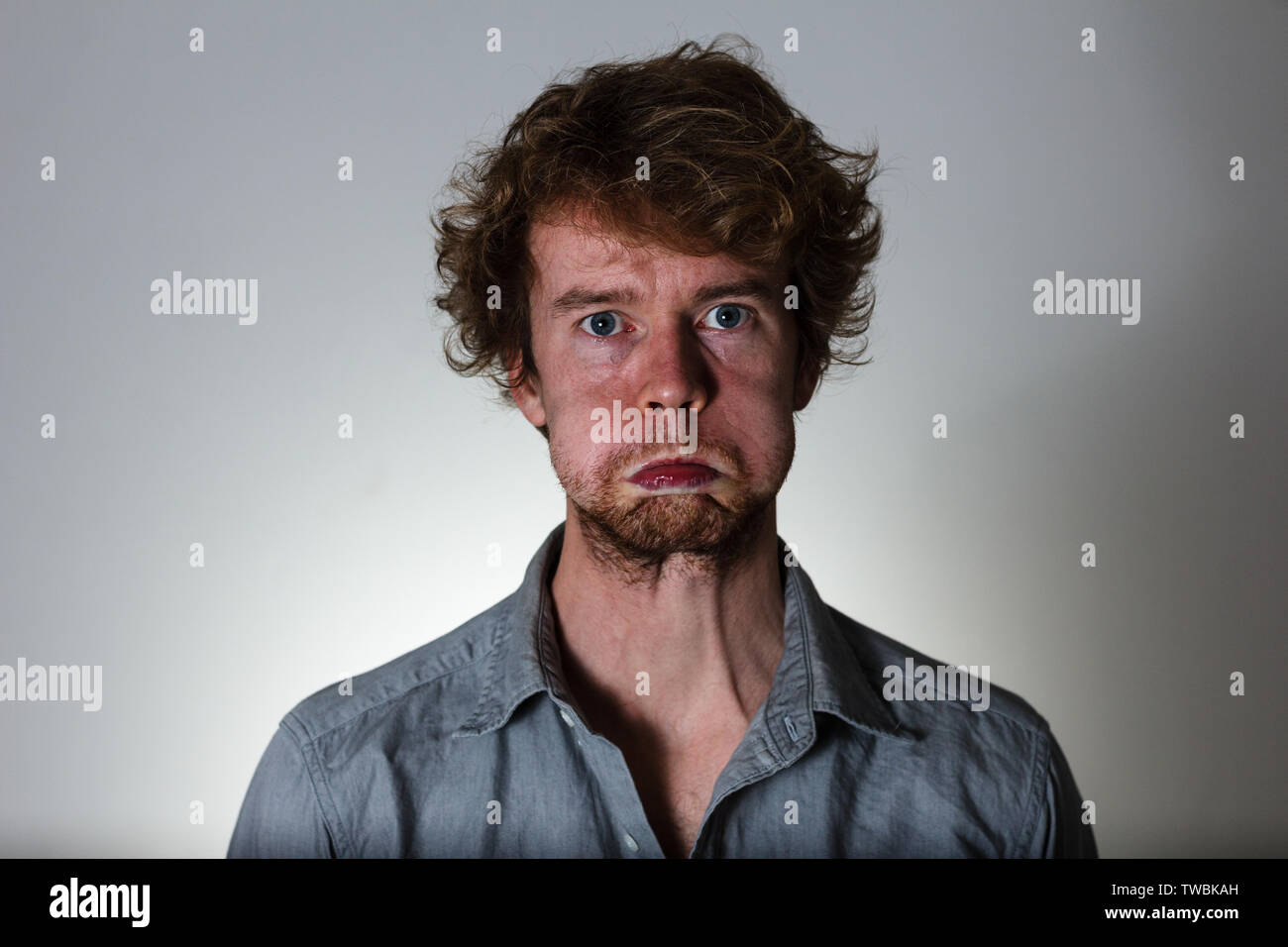 Weird expression young man on gray background Stock Photo