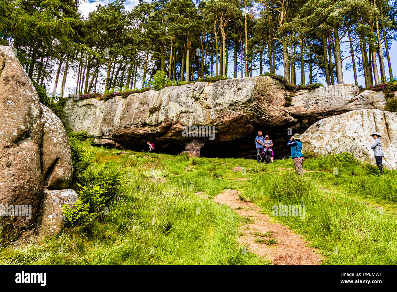 Holidaymakers and walkers enjoying St Cuthbert's Cave, a sandstone outcrop in Northumberland, UK. June 2019. Stock Photo