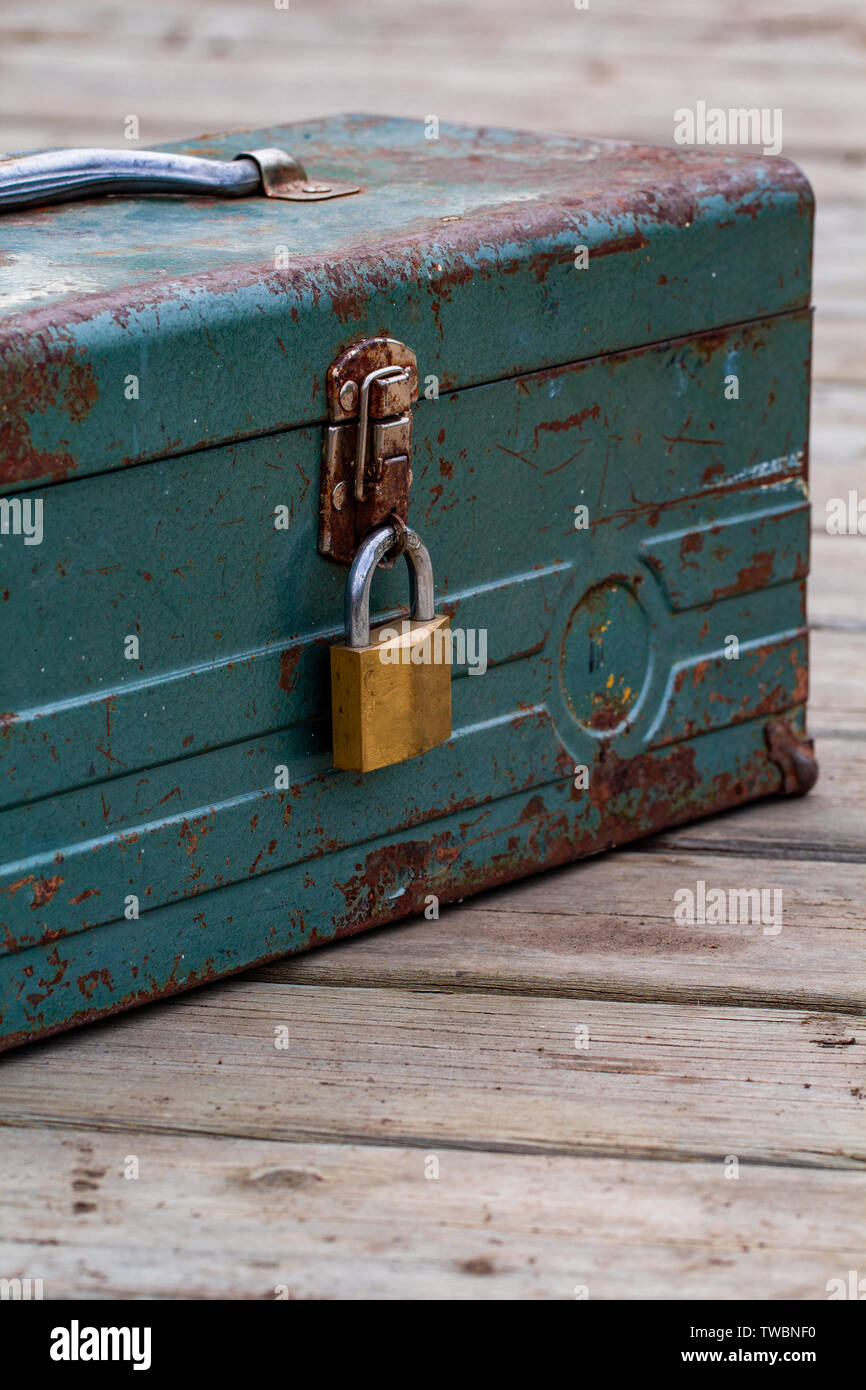 Rusty old toolbox locked up sitting on a wood Stock Photo
