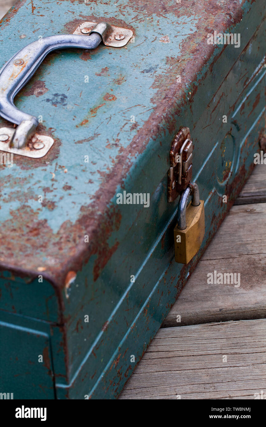 Rusty old toolbox locked up sitting on a wood Stock Photo