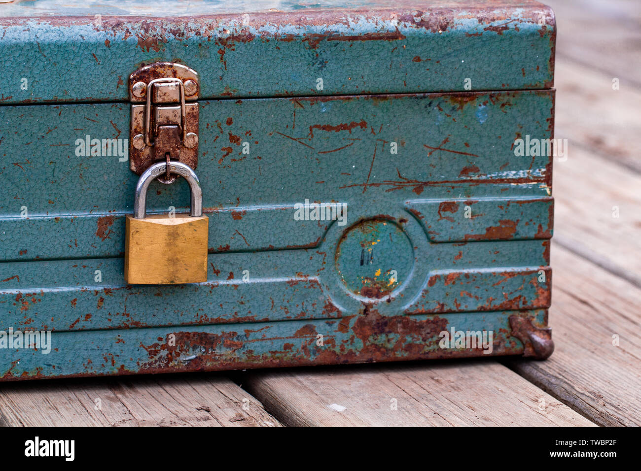 Rusty old toolbox locked up sitting on a wood Stock Photo