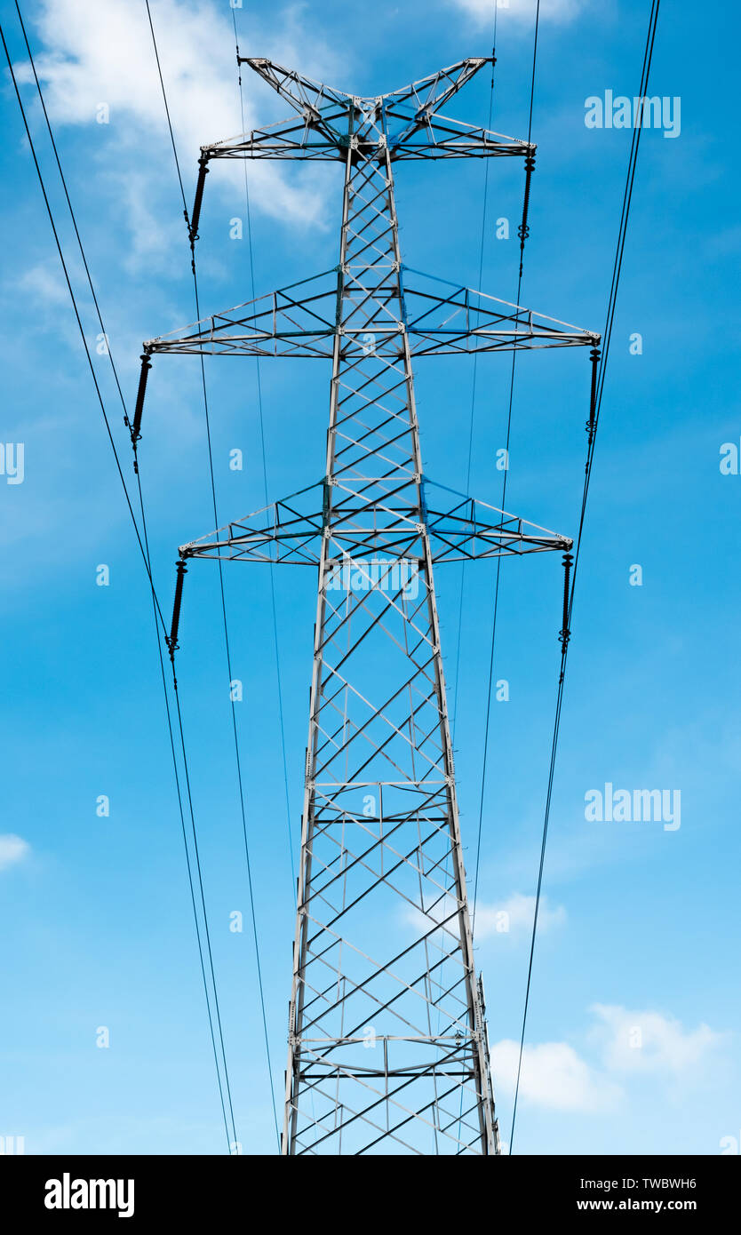 Bottom view of a high-voltage electricity pylon against blue sky with clouds at sunny day. High-voltage power transmission tower. Power engineering. Stock Photo