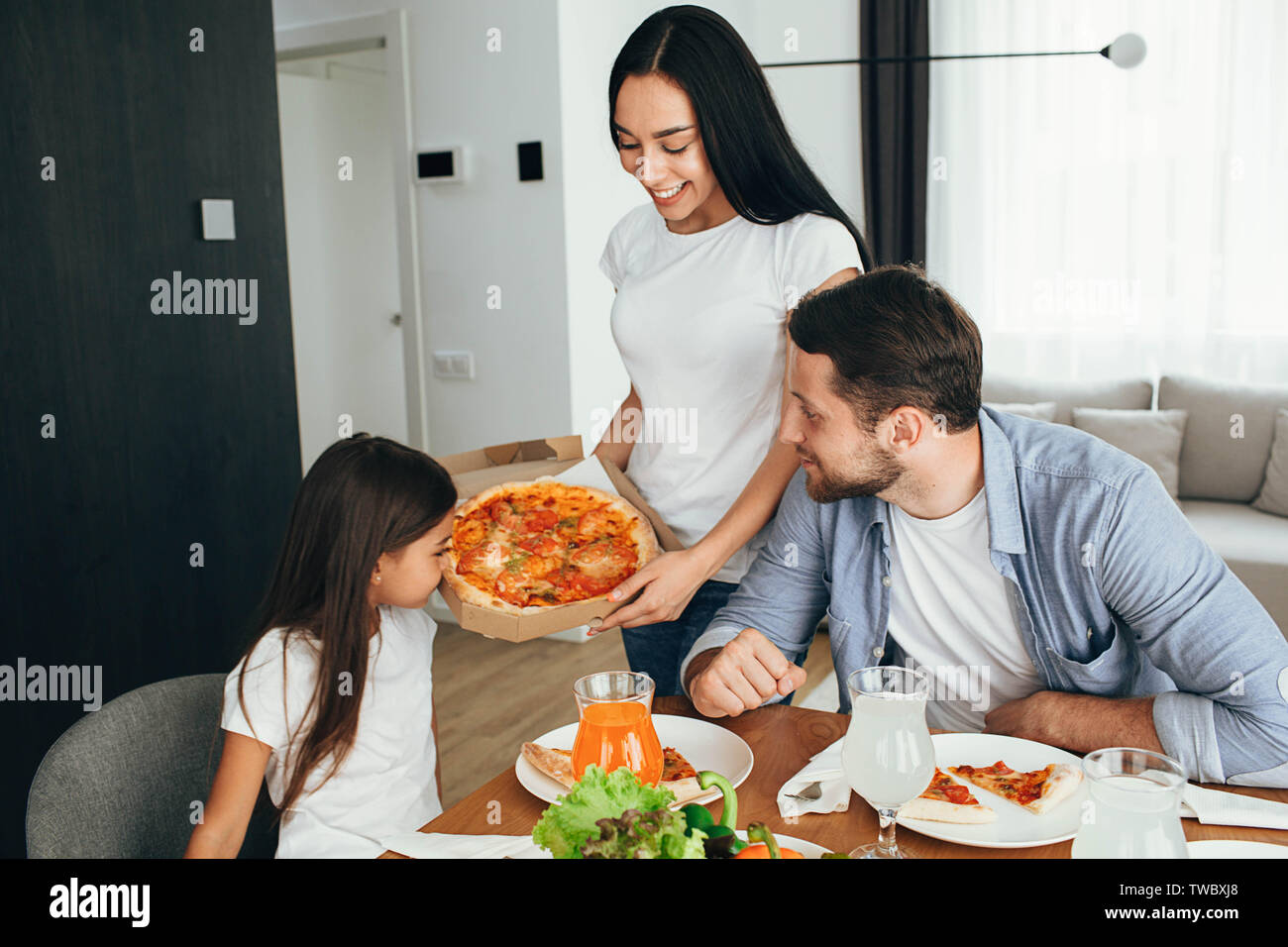 Family enjoying pizza lunch. Father, mother and daughter during dinner.Eating delicious pizza with family Stock Photo