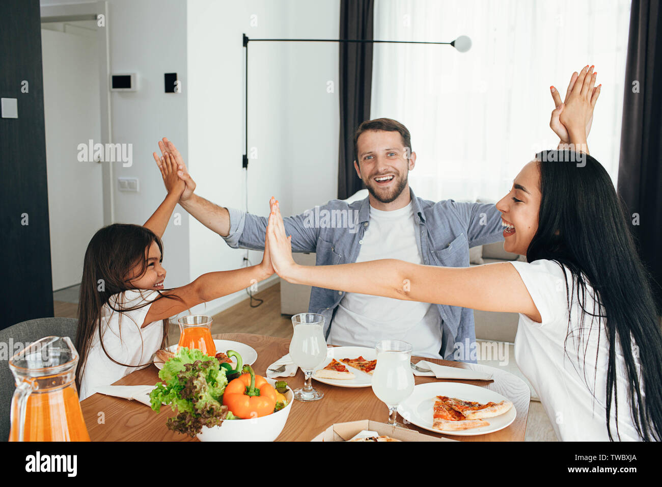 happy multi ethnic family, mother, father and daughter during dinner.Eating delicious pizza with family Stock Photo