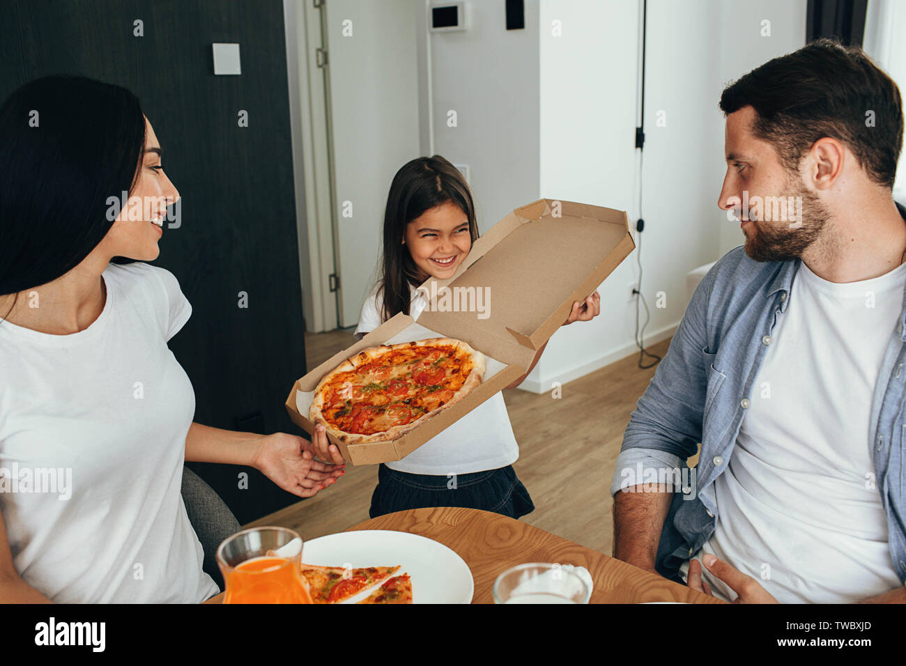 Family enjoying pizza lunch. Little girl having fun with her family Stock Photo