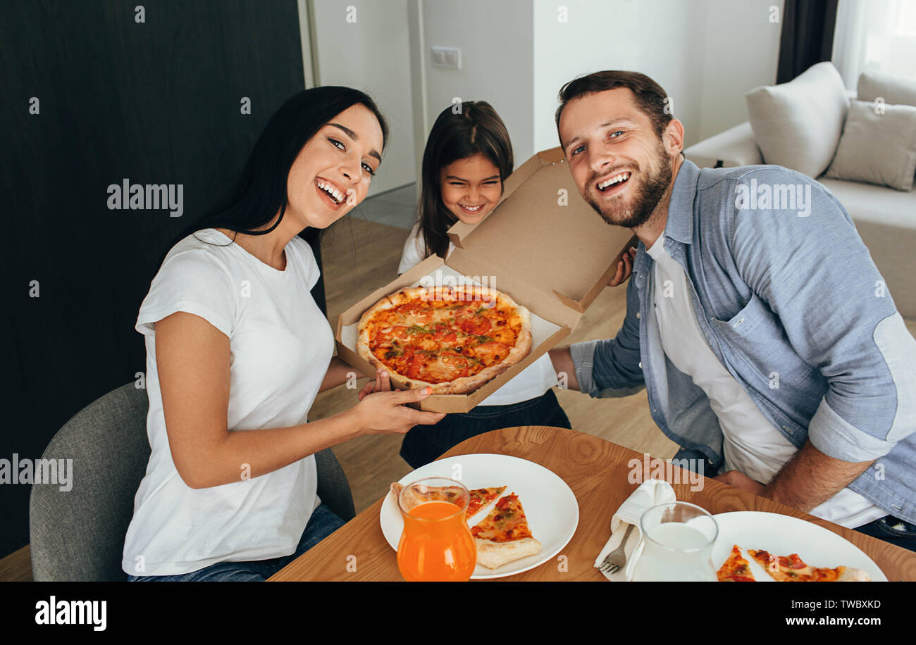 Family enjoying pizza lunch. Little girl having fun with her family Stock Photo