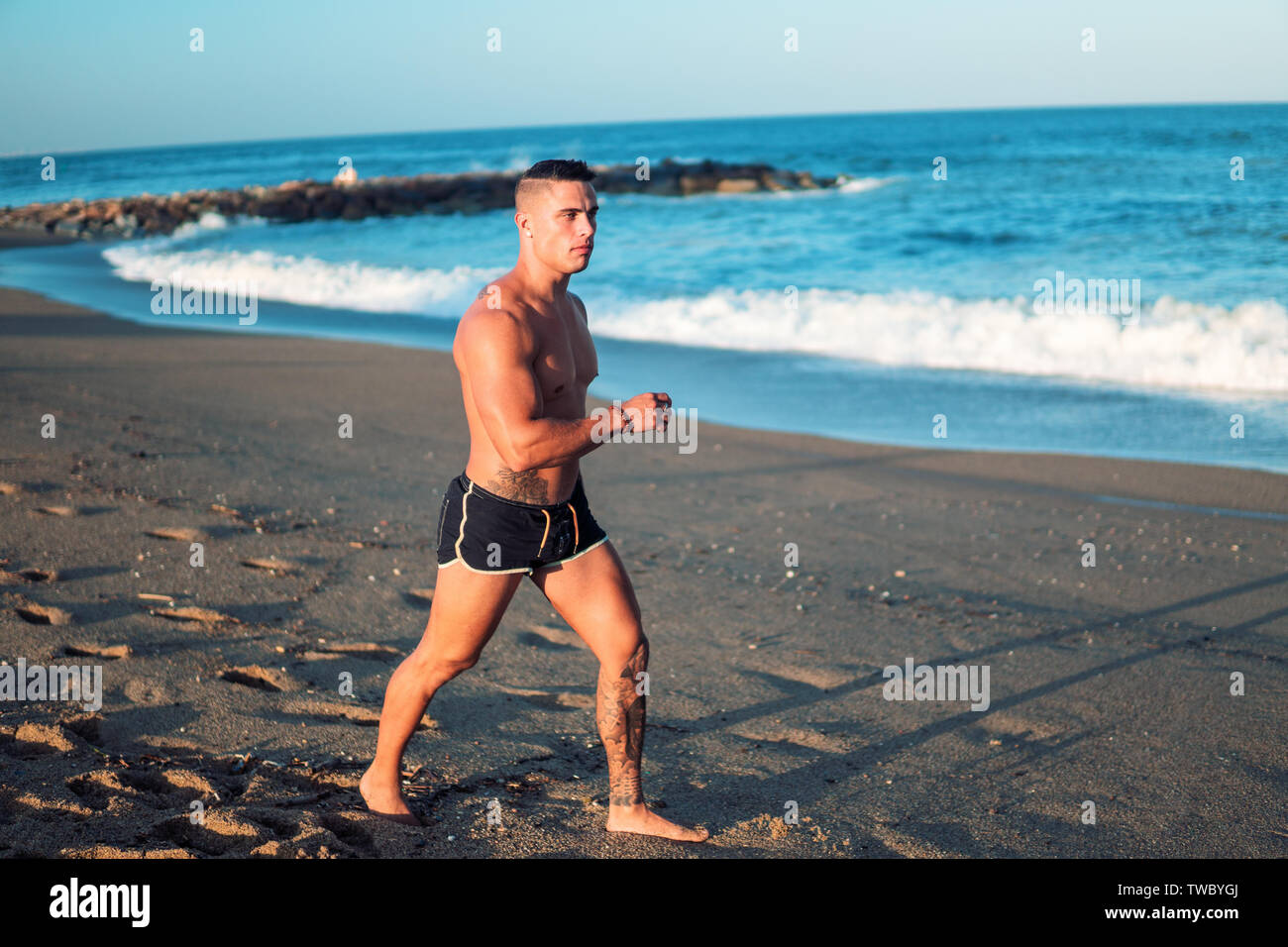 Tattooed bodybuilder sexy male coach at the beach. Stock Photo
