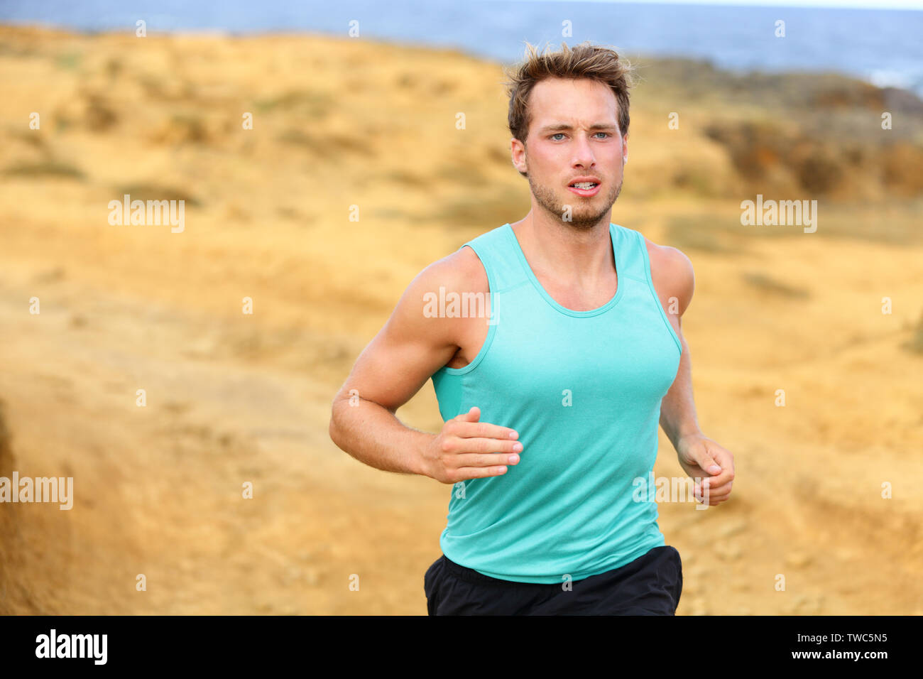Man running outdoors in nature. Fit male runner jogging outside training cross country trail running. Handsome male sports fitness model in his 20s. Stock Photo