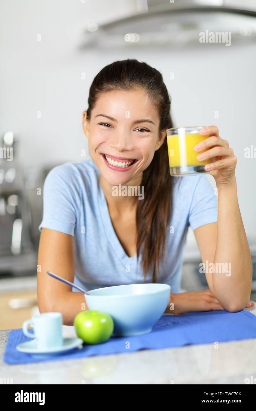 Woman drinking orange juice eating breakfast smiling happy looking at