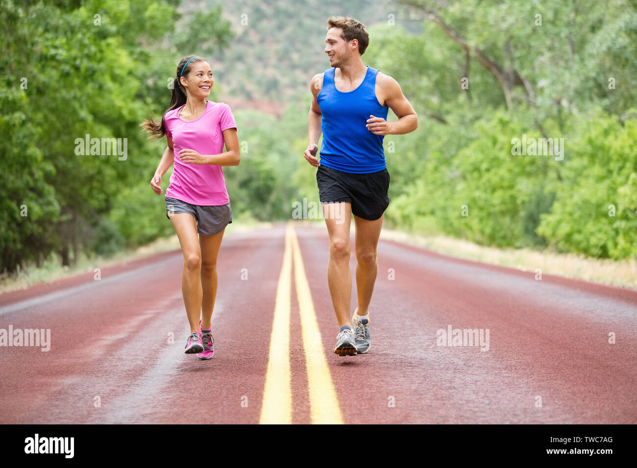 Running exercising couple jogging and talking outside on road