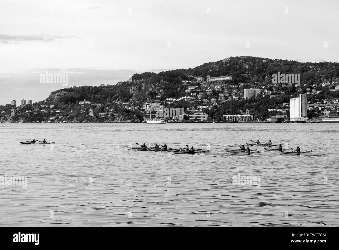 Group of kayakers at Byfjorden, outside port of Bergen, Norway. Tall ship Statsraad Lehmkuhl in background. Stock Photo