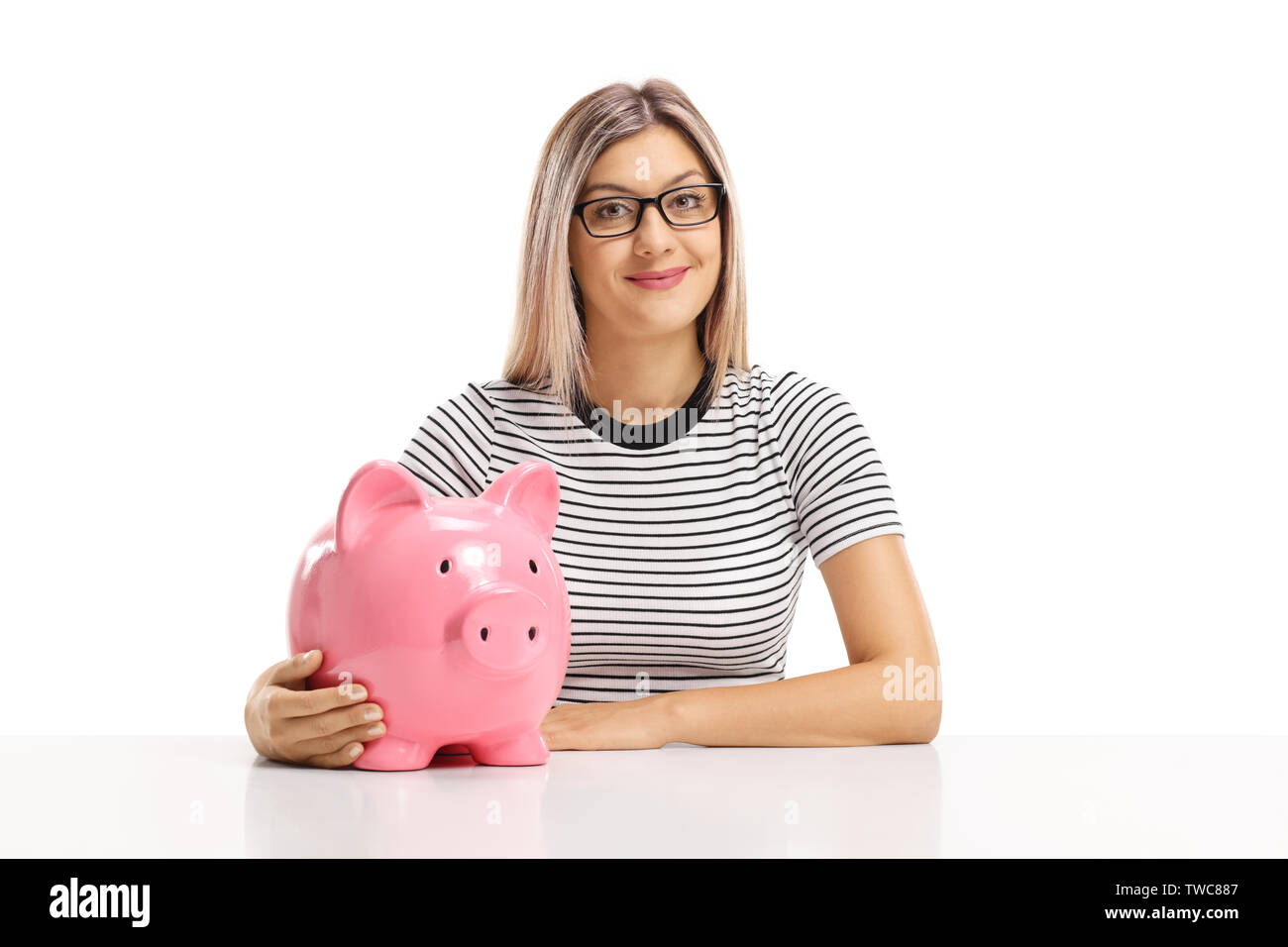 Blond woman sitting with a piggy bank and smiling at the camera ...