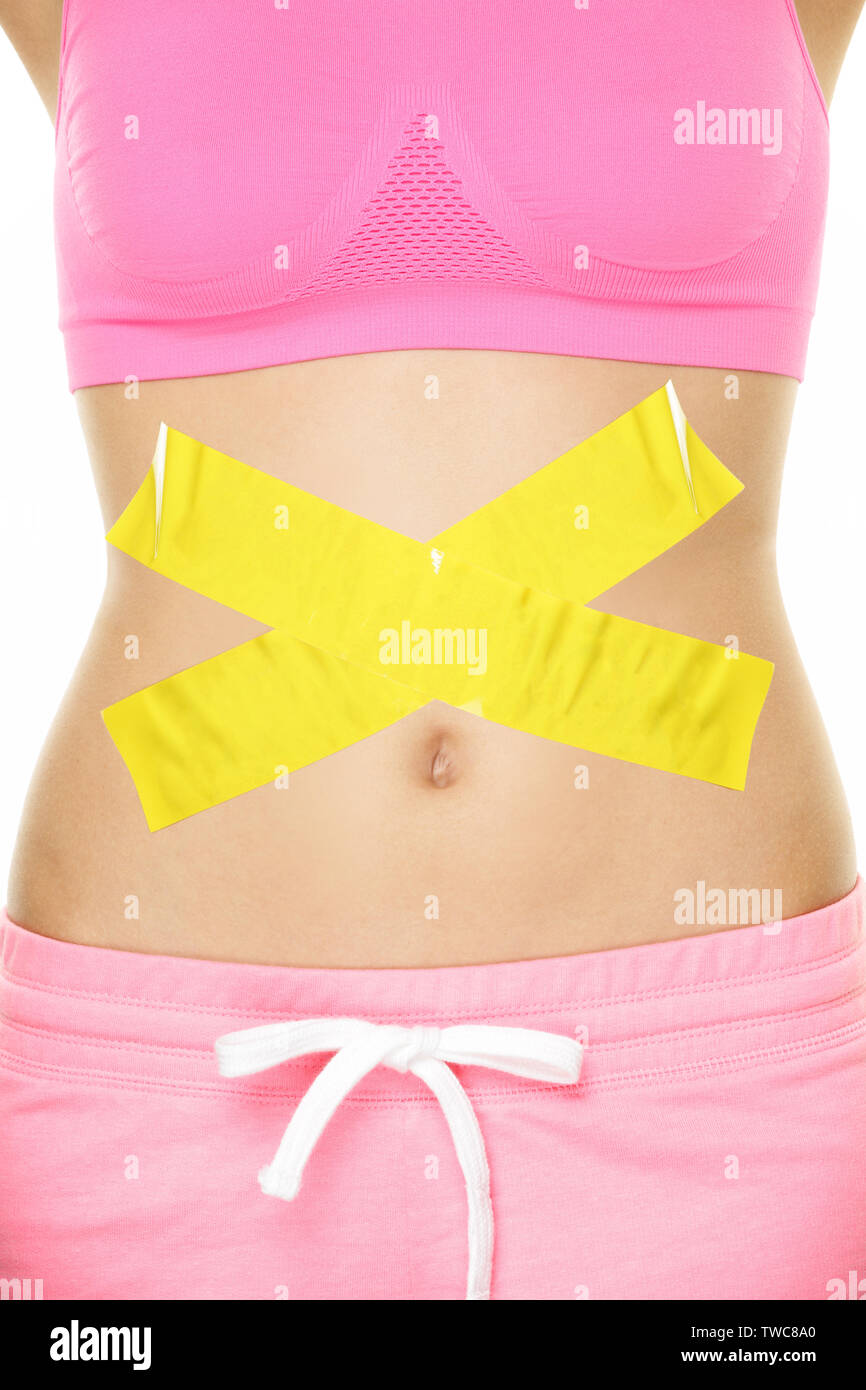 Stomach pain health digestion problems concept with tape crossed over woman belly. Take care of your body, food poisoning or other concept. Conceptual healthy lifestyle image. Stock Photo