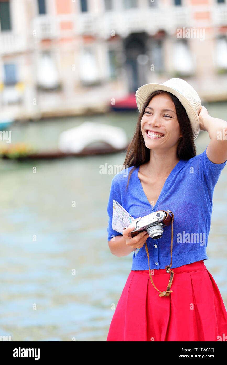 Travel woman tourist traveling in Venice, Italy holding camera and map. Asian girl on vacation smiling happy by Grand Canal. Mixed race Asian Caucasian girl having fun during holidays in Europe. Stock Photo
