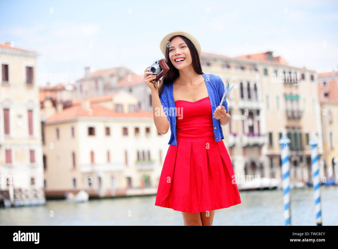 Travel tourist woman with camera and map in Venice, Italy. Girl on vacation smiling happy by Canal Grande. Mixed race Asian Caucasian girl having fun traveling outdoors during holidays in Europe. Stock Photo