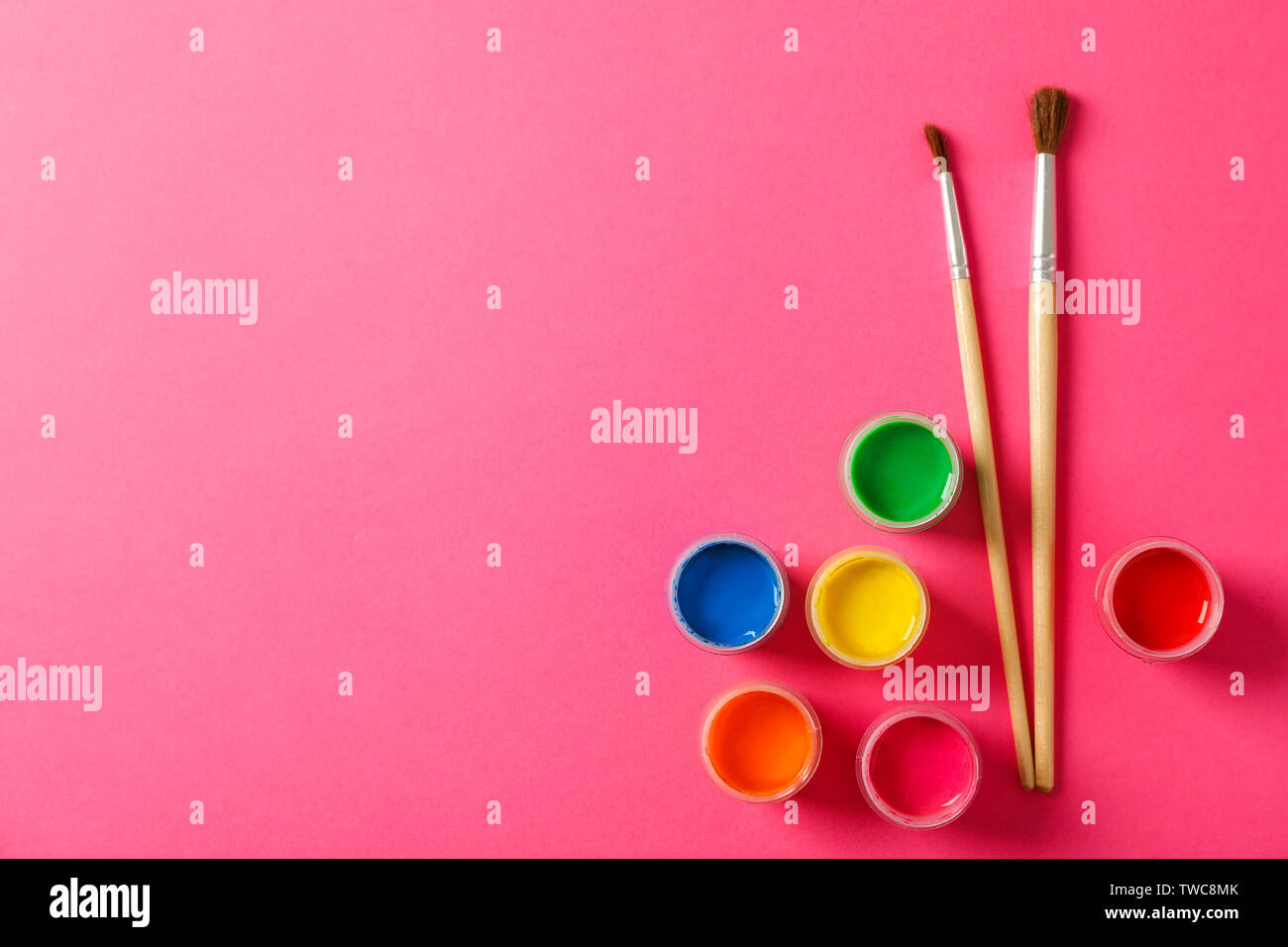 Flat lay composition with gouache and paint brushes on pink background, space for text Stock Photo
