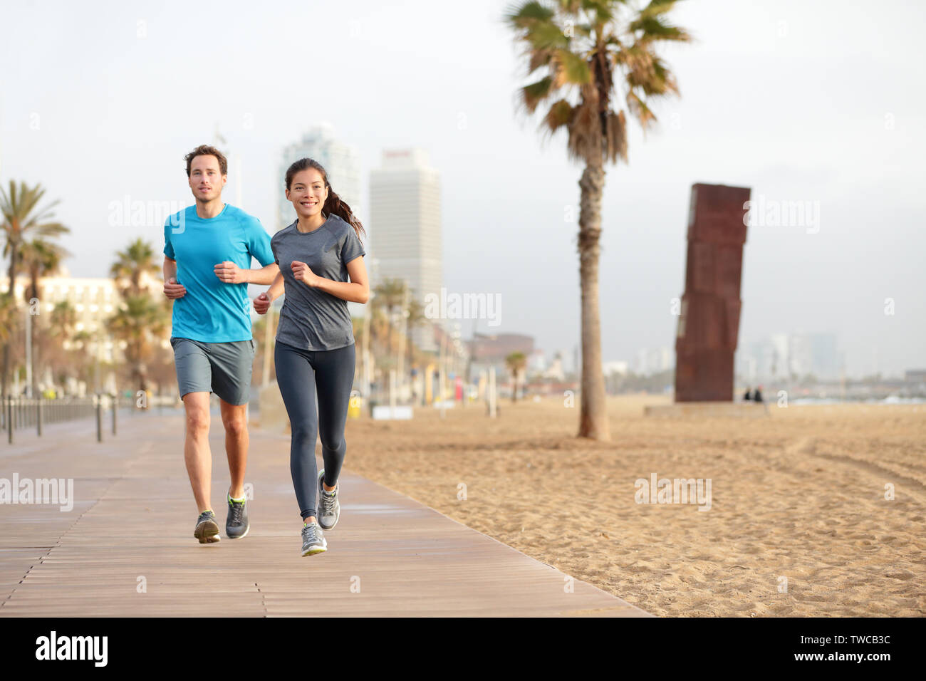 Running couple jogging on Barcelona Beach, Barceloneta. Healthy lifestyle  people runners training outside on boardwalk. Multiracial couple, Asian  woman, Caucasian fitness man working out, Spain Stock Photo - Alamy