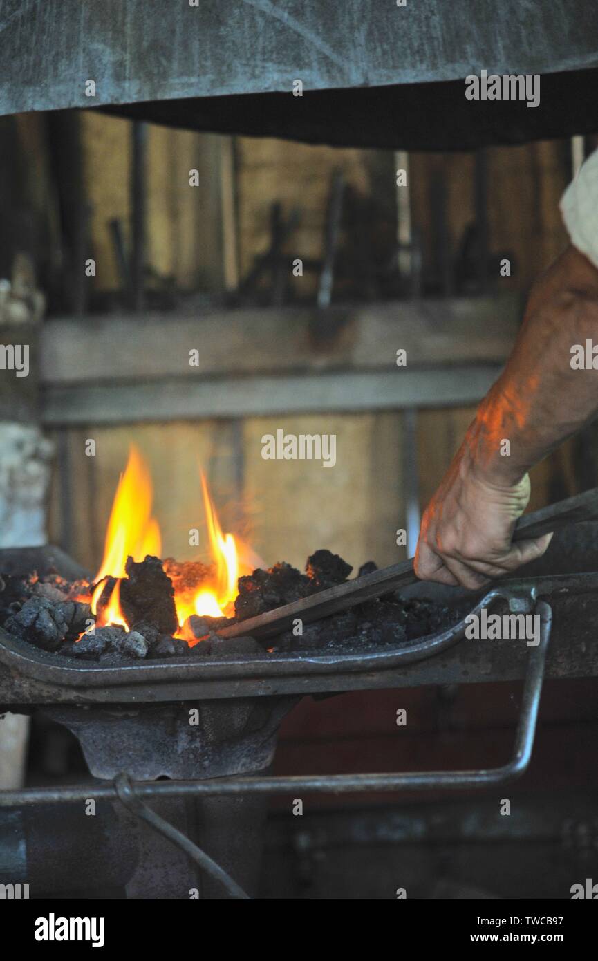 Close up of flames with male blacksmith forge at work making metal shapes in his blacksmith workshop, Hillsboro, Wisconsin, USA. Stock Photo