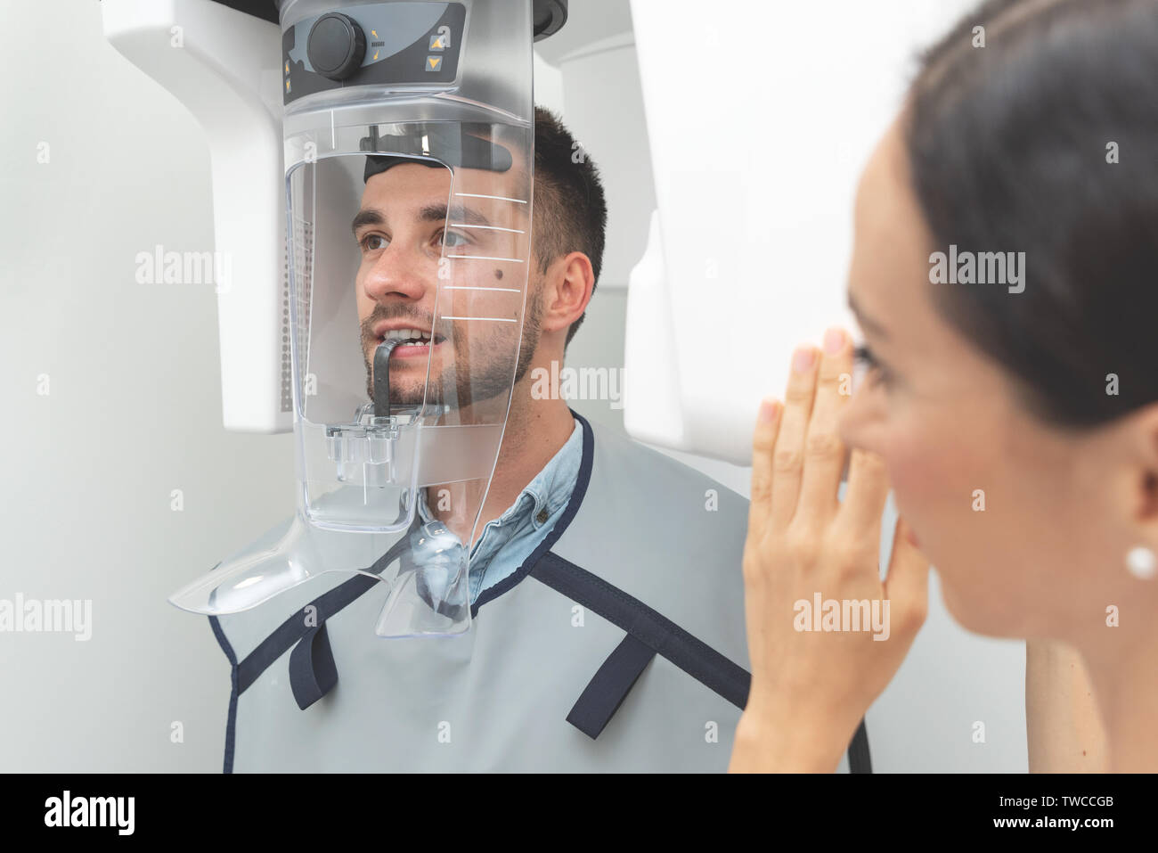 Handsome man patient standing in x-ray machine. Panoramic radiography at professional dental clinic. Stock Photo