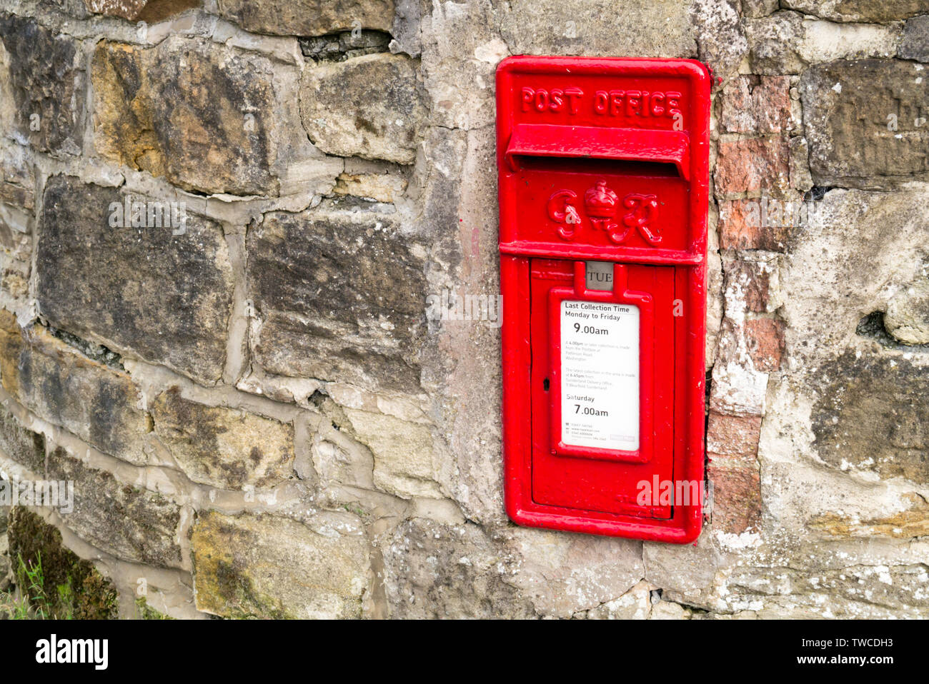 A Red George VI UK Post Box Set into a Stone Wall Stock Photo