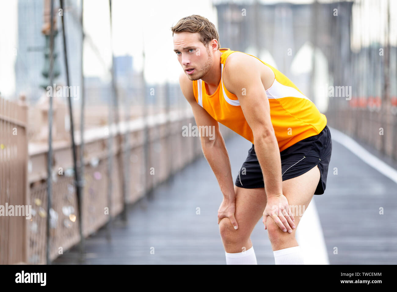 Running man resting after run in New York City. Runner training and jogging  outside taking a break. Caucasian male runner and fitness sport model on  Brooklyn Bridge, New York City, USA Stock
