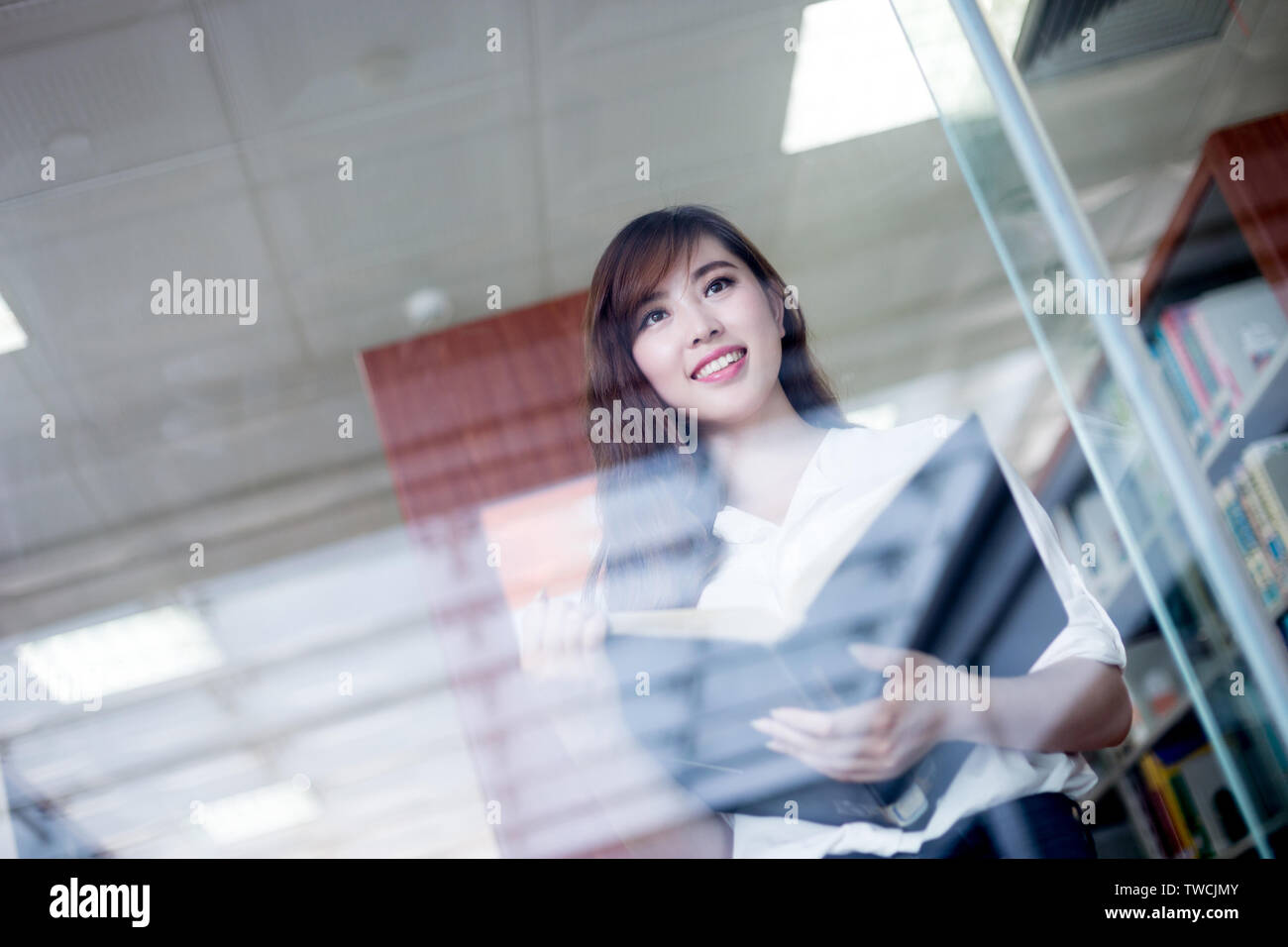 Asian beautiful female student holding book in library Stock Photo - Alamy