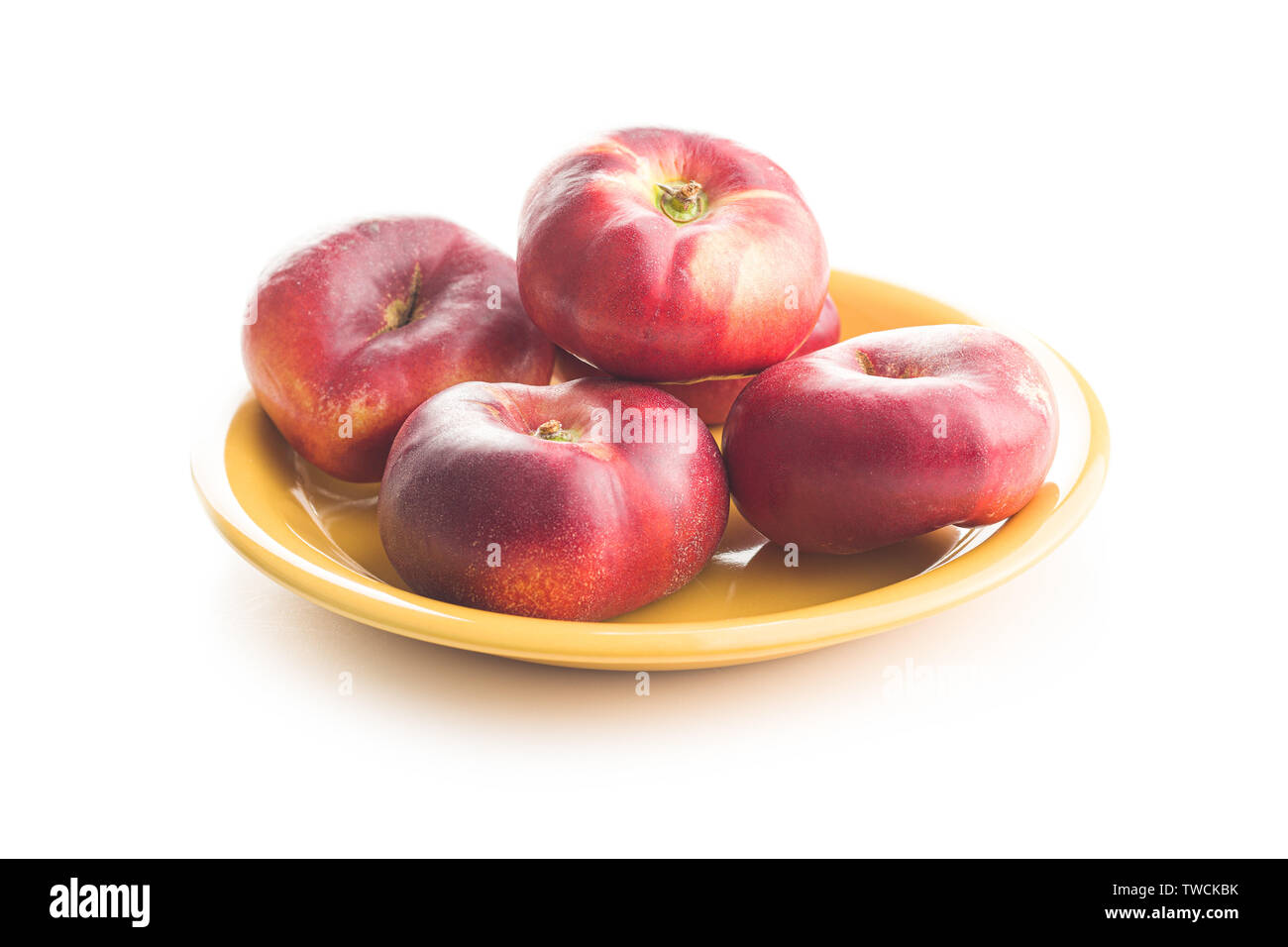 Ripe flat nectarines on plate isolated on white background. Stock Photo