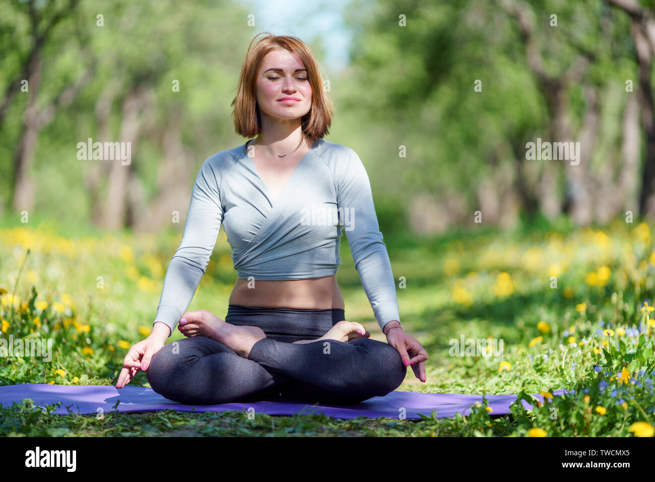 Photo of young girl doing yoga sitting in lotus position on blue rug in ...