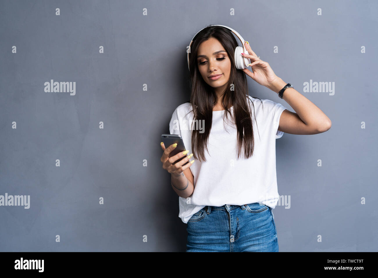 Smiling woman listening music in headphones and using smartphone over ...