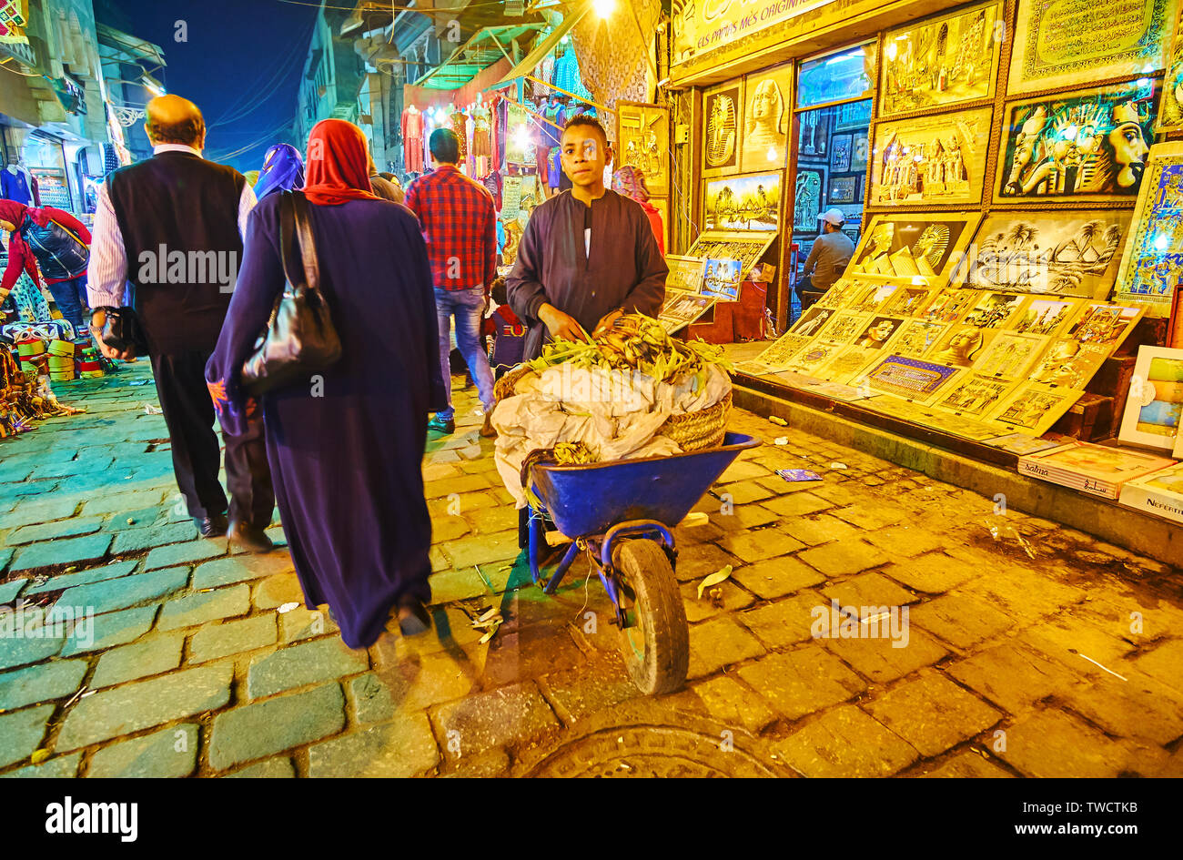 CAIRO, EGYPT - DECEMBER 22, 2017: Teenager vendor of grilled corn walks with his wheelbarrow along the souvenir stalls of Souk Khan El Khalili in Al-M Stock Photo