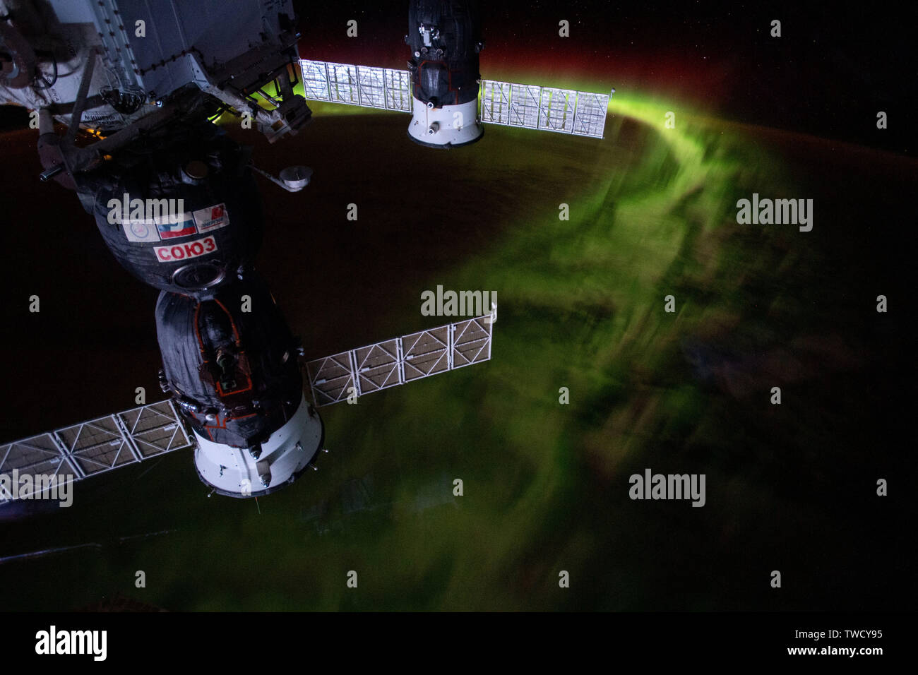Two docked Russian spaceships, the Soyuz MS-12 crew capsule (foreground) and the Progress 72 resupply ship docked at the International Space Station with the aurora australis or southern lights shining below June 8, 2019 in Earth Orbit. Stock Photo